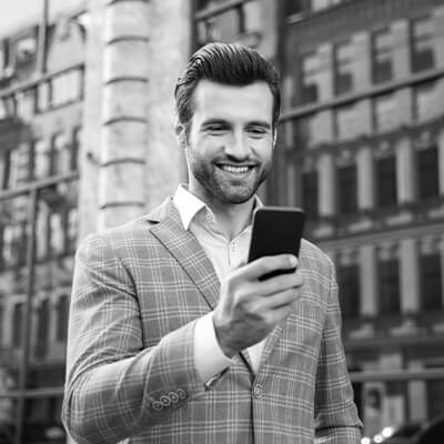 Portrait of a smiling young man in jacket looking at mobile phone